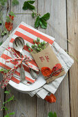 Place cards with stamped initials, with poppy blossoms and poppy pods on a place setting