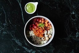 A healthy bowl with tomatoes, lentils, tofu and carrots
