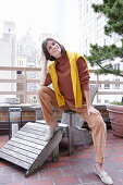 Brunette woman in autumn outfit with a yellow knitted sweater over her shoulders