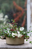 Enamel pot filled with snowberries, rosehips, heather and Mühlenbeckia