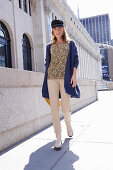 Long-haired woman in a hat in a floral blouse, a blue cardigan and light-colored pants