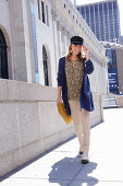 Long-haired woman in a hat in a floral blouse, a blue cardigan and light-colored pants