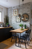 Küchenunterschrank mit schwarzer Front und Esstisch mit Stühlen, darüber Pendelleuchten