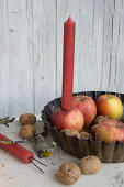 Apple as candle holder in a baking dish with walnuts