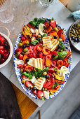 Mixed tomato salad with halloumi, burrata, fruits, and olives