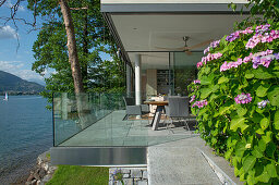 Sonnenbeschienene Terrasse mit Glasbrüstung am See