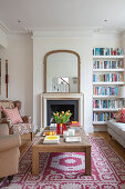 View over wooden coffee table to fireplace with a mirror next to a bookshelf in the living room