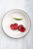 Halved cherry with leaf in white bowl
