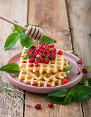 Waffles with wild strawberries, red currants, and honey