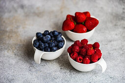 Bowl with healthy strawberries, blueberries and raspberres on concrete table
