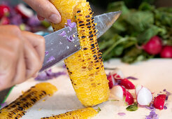 Scraping grilled corn on the cob