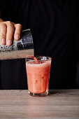 Pouring watermelon cocktail in a glass