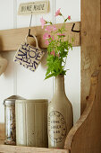 Wooden shelf holding canisters, vase with flowers and a mug