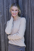 Young blond woman in striped shirt in front of board wall