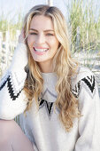 Young blond woman in light-coloured knitted dress with Norwegian pattern