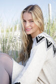 Young blond woman in light-coloured knitted dress with Norwegian pattern