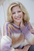 Reife blonde Frau im Strickpullover mit Farbverlauf