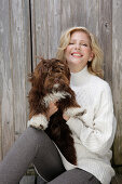 Reife blonde Frau mit Hund in weißem Strickpullover und grauen Leggins