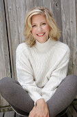 Mature blonde woman in white knitted jumper and grey leggings