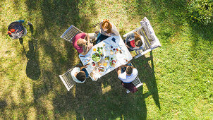 Junge Freunde sitzen zusammen am gedeckten Gartentisch