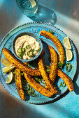 Spicy corn ribs with an avocado dip topped with chillis and lime