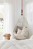 Bed with white bed linen and hanging chair in the bedroom