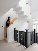 Weißes Treppenhaus mit schwarzem Geländer, Mann auf der Treppe