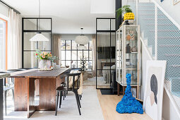 Dining area with wooden table and glass cabinet, glass paneled wall in industrial style as room divider