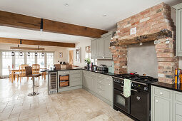 Light colored country style fitted kitchen cabinets in the corner, dining area in the background