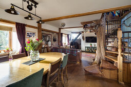 Dining area and wooden staircase in an open plan living room with tree trunk