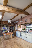 Offene Küche mit rustikalen Holzbalken und Metzgerblock