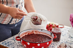 Pour hot strawberry jam into a glass