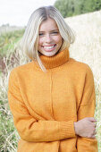 Junge blonde Frau in gelbem Rollkragenpullover in der Natur