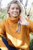 Junge blonde Frau in gelbem Rollkragenpullover in der Natur