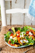 Summer salad with fresh apricots, mozzarella, olives, roasted tomatoes, and basil