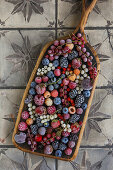 Frozen berries (raspberries, blackberries, currants) and cherries on a wooden scoop