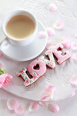 Schriftzug 'LOVE' aus glasierten Lebkuchenplätzchen neben einer Tasse Espresso
