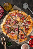 Pizza with salami, ham, and tomatoes
