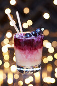 Alcoholic festive fresh blueberry syrup Christmas cocktail in a lowball glass garnished with blueberries