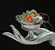 Prawn with silver leaf in a silver bowl on a silver decorative hand