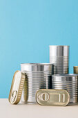 Stacked unopened metal cans on blue background