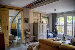 Living room with mustard yellow sofa, armoire, and tripod lamp in front of patio door