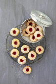 Linzer cookies on a cooling rack and in a cookie tin