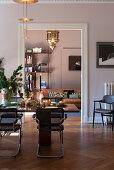 Festively laid Christmas table with cantilever chairs, in the background view into the living room