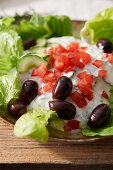 Tzatziki mit Paprikawürfeln, Salatblättern und Oliven