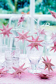 Glasses with red and white star-shaped fairy lights on table