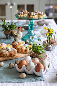 Chicken eggs in a ceramic container, quail eggs and yeast wreath nests with Easter eggs