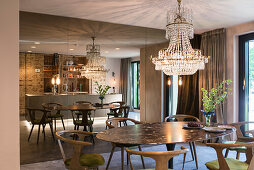 Dining area with designer table and chairs, above chandelier in front of mirrored wall