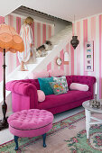 Pinkfarbenes Sofa in Lounge mit rosa gestreifter Tapete, weiße Treppe mit Frau und Hund