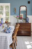 Set table with rattan chairs and dresser in dining room with blue walls and white tiles